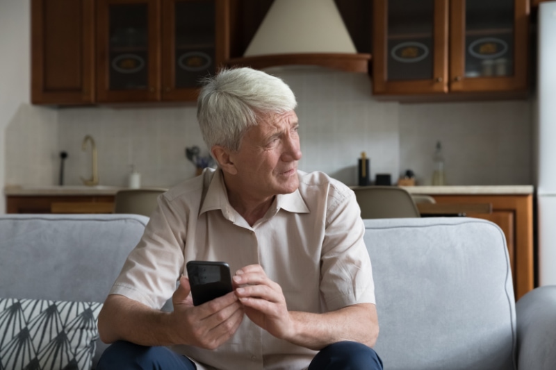 Worried senior citizen with a smartphone looking concerned.