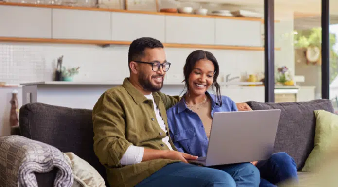 Happy couple sitting on couch with laptop in Waldorf, MD.